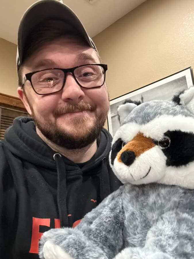 Floki grinning with a plush raccoon